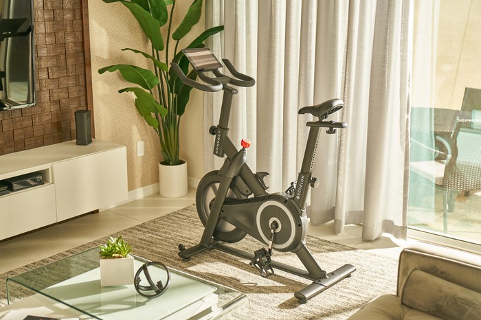 The Prime Bike in a furnished room with a sliding glass door and curtains behind it